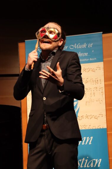 Künstler mit einer humorvollen Maske auf der Bühne beim Sommerfest der Musikschule Aachen.
